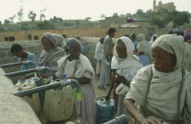Women filling containers at water point.