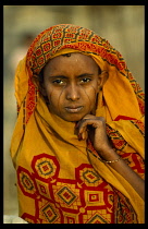 Portrait of Eritrean refugee woman with facial scarification and wearing block printed ochre coloured head covering. Colored