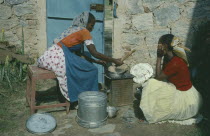 Women cooking over charcoal.