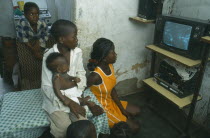 Bairro of Cacuoca.  Fifteen year old Maria Lydia at home watching television with her siblings.  Her family are unable to afford school fees.