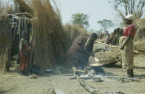 Hutu village in the jungle with women cooking at open fire and watching children. Zaire