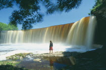 Young woman standing in front of Jgala  steep horseshoe shaped waterfall between Tallinn and Lahemaa National Park