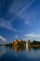 Lithuania, Trakai, wide angle view of castle reflected in lake with windswept clouds above.