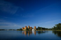 Lithuania, Trakai, wide angle view of castle reflected in lake with windswept clouds above.