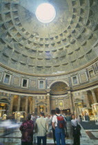 Pantheon.  Interior of Roman temple  visitors looking up at circular opening or oculus in domed ceiling leeing in beam of light.