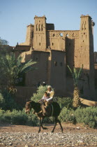 Kasbah used in films including Lawrence of Arabia and Jesus of Nazareth.  Exterior with passing man and boy riding mule in foreground.UNESCO World Heritage site