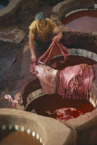 Chouwara Tanneries.  Man working in the tanner s pits using red dye.Fez