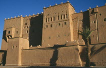 Kasbah Taorirt .  Nineteenth century kasbah of the el-Glaoui dynasty.  Exterior view with shadow from palm tree in foreground.