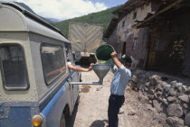 Purchasing gasoline in the highlands. Man pouring gas through a funnel into van.Petrol