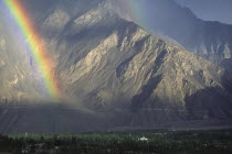 Rainbow  with mosque lit up by sun.