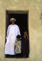 Sheikh of Al-Ghalila with his two children in the doorway to his house.