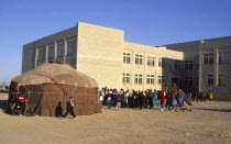 Yourt in Kazakh playground  with children and school behind.yurt  yurta  a nomads tent made of felt.