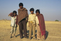 Group of young boys in the desert  some with blankets round them.