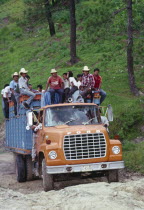 Ford truck full of campesino men climbing a steep incline.