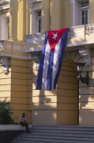 Security guard sat outside government building  flying Cuban flag.