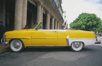 A classic yellow US 1950s car  parked on the Malecon.