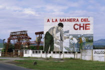 Billboard celebrating the work of Che Guevara  with industrial facilities behind.