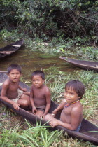 Three tukano Indian boys sat in canoe. Vuapes