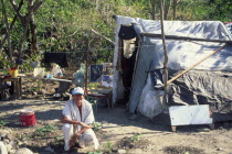 Squatter  attracted by oil boom  outside his temporary housing.