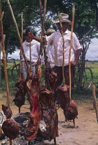 Carne a la llanera  A group of men with cooked meat on sticks.