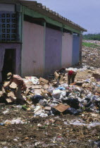 Two people searching through rubbish  waste collection site.