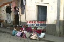 Indigenous women and children sat on pavement outside trekkers agency internet cafe.