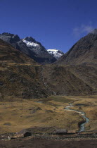 Settlement with mountains behind with snow on the peaks.Illampu circuit