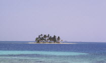 A sandy isolated island covered in palm trees in the distance.