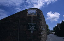 St Saviours. Convex mirror on stone wall with reflection of a small white cottage