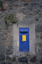 Traditional blue post box on wall.