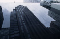 USA, New York, Manhattan, Exterior of the Museum of Modern Art in West 53rd Street with the opposite building reflected in the dark glass facade.