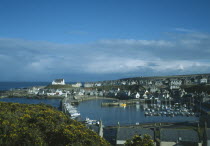 Fishing village on north coast with pleasure boats moored within harbour walls and gorse in flower in the foreground.