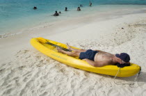 Man lying in kayak sunbathing on the beach of Petit Bateau