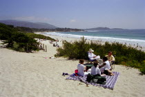 Carmel Beach with people on blanket among sand dunes in the foreground