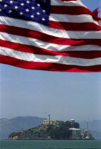 Alcatraz Island and Prison in San Francisco Bay with stars and stripes flag flying in the foreground above