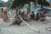 Pygmies in forest near Ituri.  Man in foreground smoking dried local leaves in long bamboo pipe. Zaire