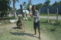 Boys playing cricket with home made bat and wickets.