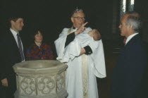 Church of England baptism.  Priest makes sign of the cross on the babys forehead with holy water from font.