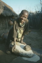 Dodoth Karamojong girl grinding millet on stone.Pastoral tribe of the Plains Nilotes group related to the Masi