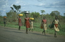 Acholi girls walking down the road some carrying baskets on their heads