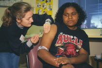 Aboriginal girl receiving Rubella vaccination from female nurse.