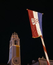 View looking up at the Clocktower illuminated at night with Croatian flag in the foreground