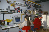 Young kids using computers in bedroom.