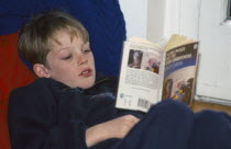 Boy reading a paper back book