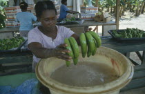 Woman dipping bunches of bananas in ripening agent at the Eastern Plantation