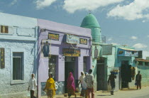 Mosque painted turquoise with domed roof situated between two tailors.  People walking past.Harer is said to have the largest concentration of mosques in the world.