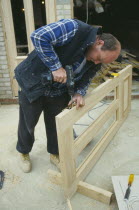 Carpenter using power screwdriver to secure hinge to door