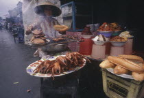 Woman cooking various meat products at market stall.