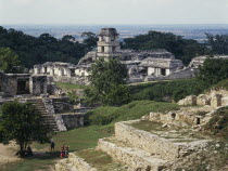 View over ruins towards the tower of the Palace in Palenque ruins  visitors walking amongst the walls.