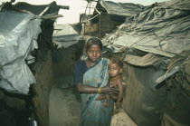 Woman holding small child in slum housing area